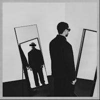 a black and white photo of a man standing in front of mirrors